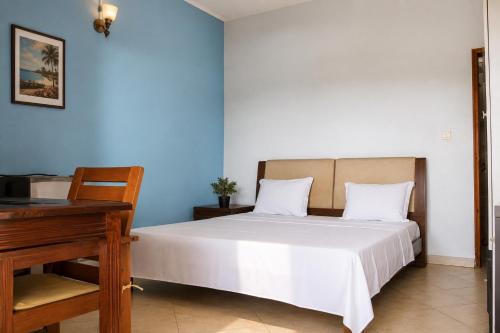 a bedroom with a white bed and a piano at Chambre à louer in Moroni