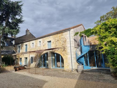 an old brick building with blue windows and a tree at Sirona - domaine viticole et chambres d'hôtes in Le Puy-Notre-Dame