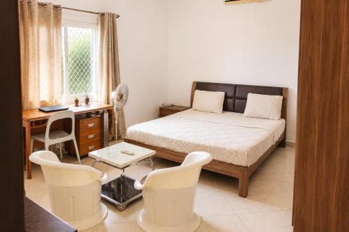 ein Schlafzimmer mit Bett, Schreibtisch und Stühlen in der Unterkunft Appartement in Moroni