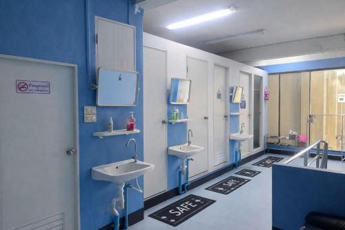 a bathroom with three sinks in a blue wall at J Cafe & Hostel in Chiang Mai