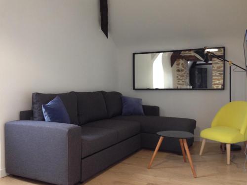 a living room with a couch and a mirror at Le Duplex des Eclusiers in Redon
