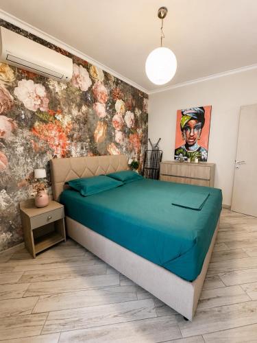 a bedroom with a blue bed and a floral wall at Luxury & Modern Apartment in Paralia Katerinis