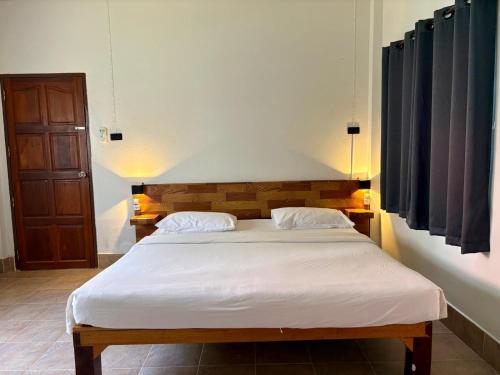 a bedroom with a large bed with white sheets at Coconut Bungalow in Nai Yang Beach