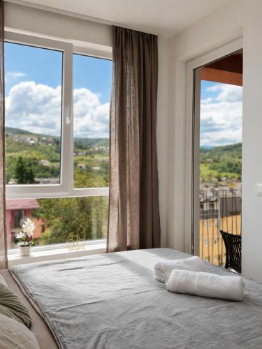 a bed in a bedroom with a large window at AURA apartment Vogošća, Sarajevo in Vogošća