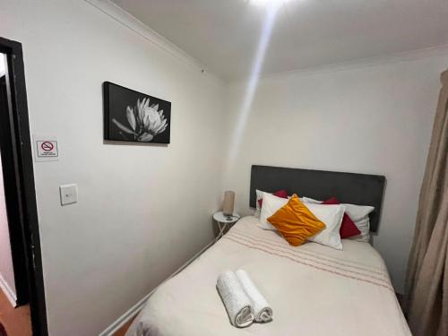 a bedroom with a bed with yellow and orange pillows at Kay's Guest House in Kraaifontein