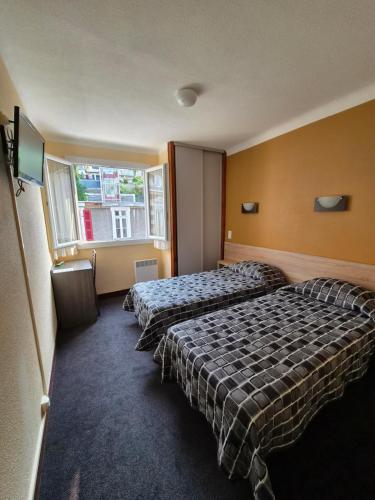 a hotel room with two beds and a window at Hôtel Saint Sébastien in Lourdes