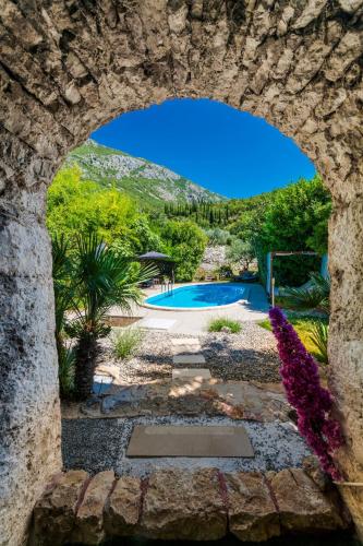 a view of a swimming pool through a stone wall at VILLA Mara in Dubravka