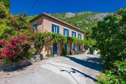 a building with blue shutters on a street with flowers at VILLA Mara in Dubravka