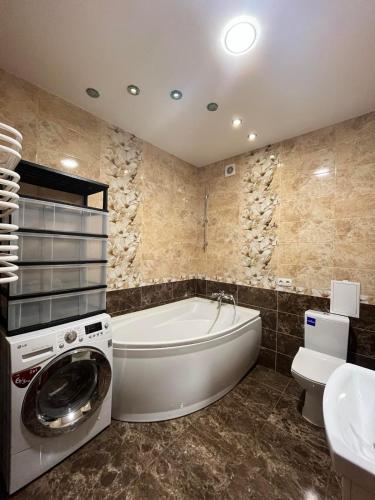 a bathroom with a tub and a washing machine at Private Apartment in Morshin