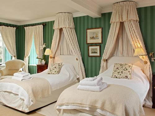ein grünes Schlafzimmer mit 2 Betten und einem Stuhl in der Unterkunft Weir House in Bruern