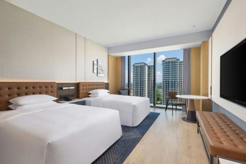 a hotel room with two beds and a flat screen tv at Four Points by Sheraton Leshan in Leshan