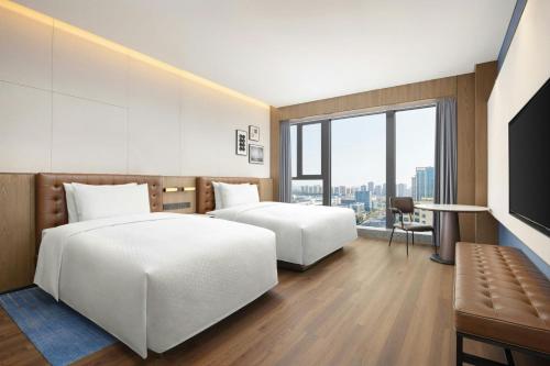 a hotel room with two beds and a television at Four Points by Sheraton Hefei, Qirui in Hefei
