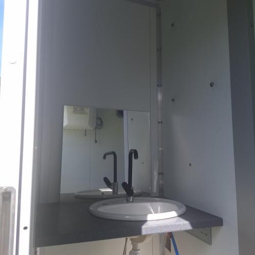 a bathroom with a sink and a mirror at Caravane Les Roches Blanches in Guenroc