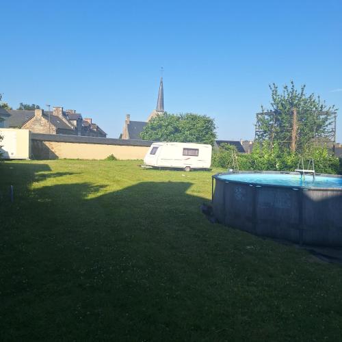 a van parked in a yard next to a pool at Caravane Les Roches Blanches in Guenroc