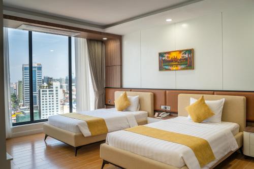 a hotel room with two beds and a large window at Champs Elysees Hotel & Suites in Phnom Penh