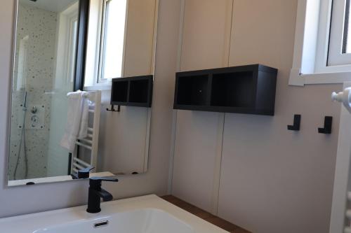 a bathroom with a sink and a television on the wall at Valterra Lodges à Châtillon-en-Diois in Châtillon-en-Diois