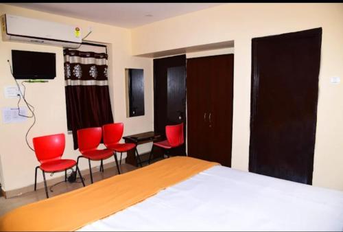 a bedroom with red chairs and a bed and a tv at Chhatrapati Residency in Tirupati