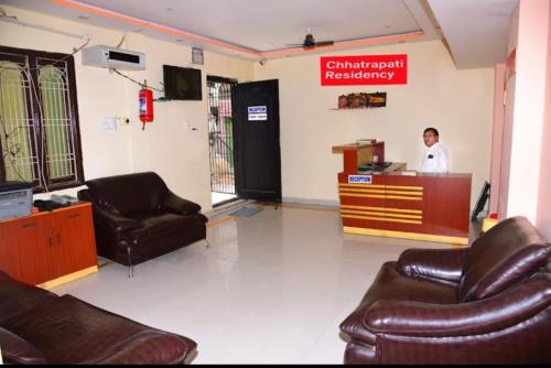 a man standing at a counter in a waiting room at Chhatrapati Residency in Tirupati