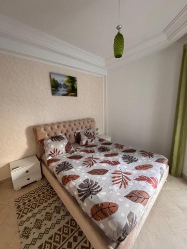 a bedroom with a bed with a flowered comforter at Front de mer Chott Mariem in Chott Meriem