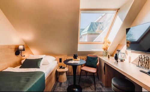 a bedroom with a bed and a desk and a window at Aqua Hotel Termál in Mosonmagyaróvár