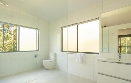 a white bathroom with a toilet and a sink at Oakey Creek Retreat in Gheerulla