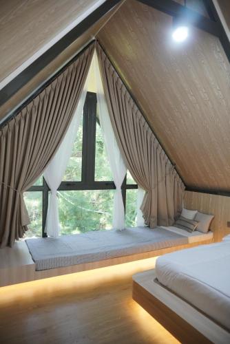 a bed in a room with a large window at Teras Bumi Cabin in Haurkuning