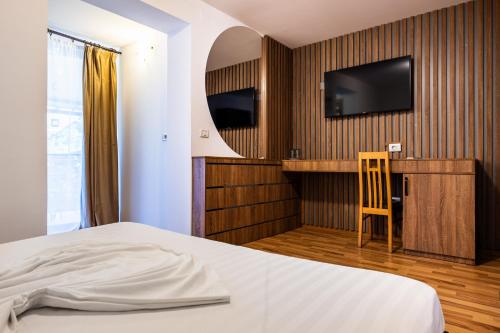 a bedroom with a bed and a desk and a television at Pensiunea ANDREI OCNELE MARI in Râmnicu Vâlcea