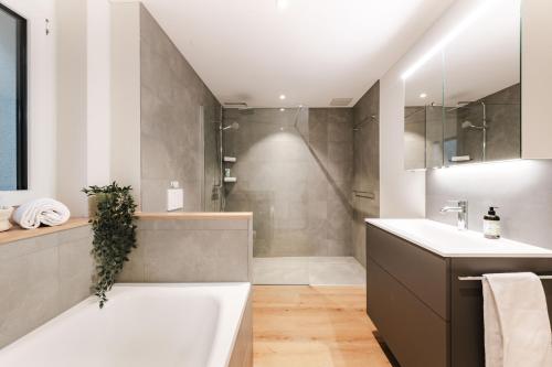 a bathroom with a tub and a sink and a shower at FLORA BAY Spacious Lake and Mountain View Apartment in Niederried