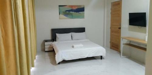 a bedroom with a white bed and a television at Pacific View Point in Matnog