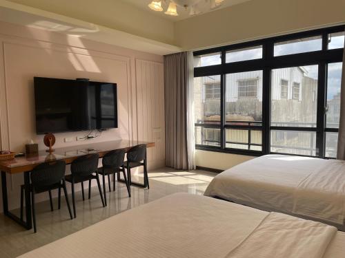 a bedroom with a bed and a desk with a television at 好客來-正市區電梯別墅步行東大夜市3分鐘公正包子1分鐘 in Hualien City