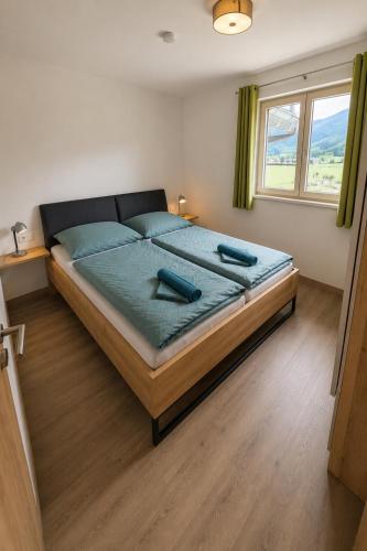 a bedroom with a bed with blue sheets and a window at Apartment Kaiblingblick in Haus im Ennstal