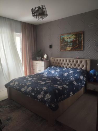 a bedroom with a bed with a blue floral bedspread at Deako in Kobuleti