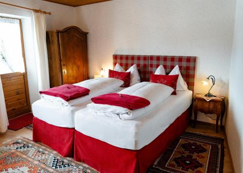 two beds in a room with red and white pillows at Ferienwohnungen Vomperberg in Schwaz
