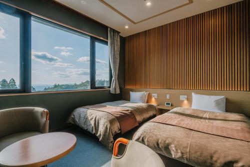a hotel room with two beds and a table and a window at Kirishima Hotel in Kirishima
