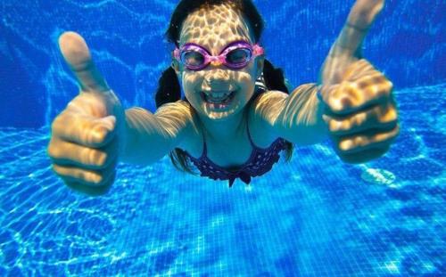a woman in a swimming pool giving a thumbs up at Qorqud Hotel - Free Massage in Baku