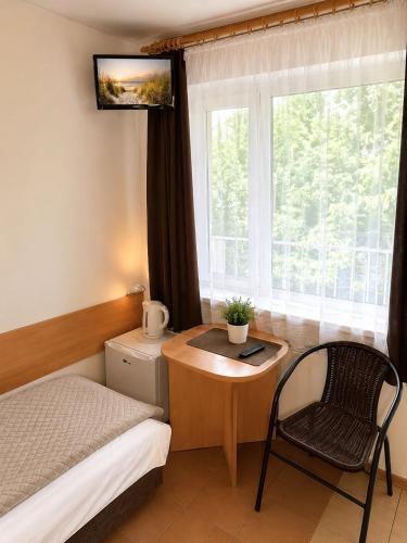 a bedroom with a desk and a bed and a window at Obłoczek in Łeba