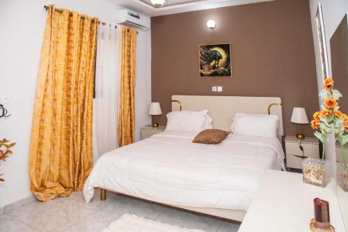 a bedroom with a white bed and yellow curtains at BRUNCH RESIDENCE BoUAKE in Kodia Kofikro