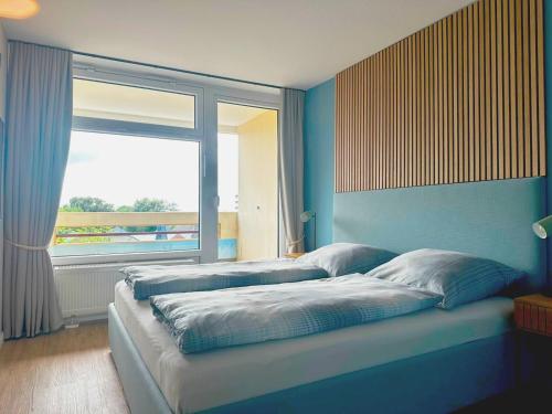 two beds in a room with a large window at Villa Anna I - Wohnung Strandjunge in Sankt Peter-Ording