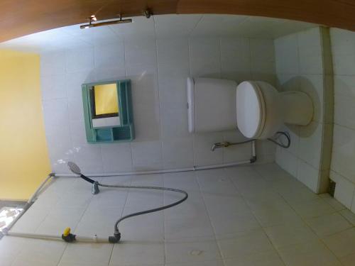 a bathroom with a toilet and a hose on the floor at Taba Yama Trip & Homestay in Ketapang