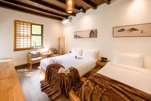 a bedroom with two beds and a chair in it at Elsewhere Hotel Inn Ancient City Center Branch in Pingyao