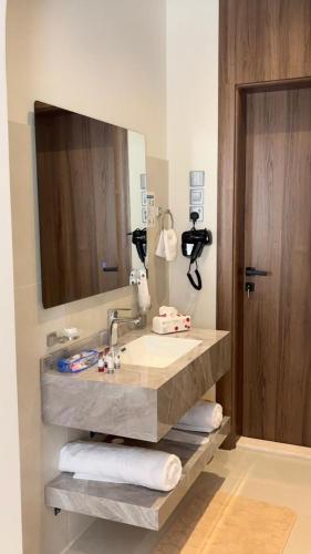 a bathroom with a sink and a large mirror at بالم هيلز Palm Hills in Baljurashi