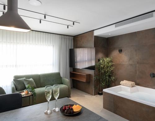 a living room with a couch and a table with wine glasses at בוטיק אשתאול - 4 סוויטות מפנקות עם ג'קוזי פרטי ו2 בריכות במתחם in Eshtaol