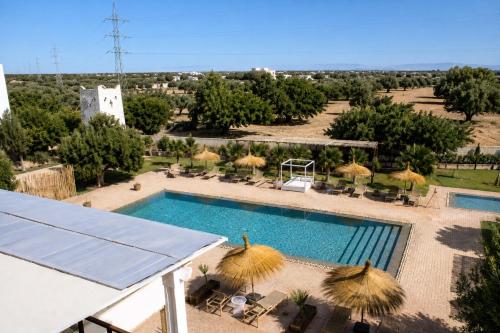 a swimming pool with straw umbrellas and a resort at Riad SABIDI in Essaouira