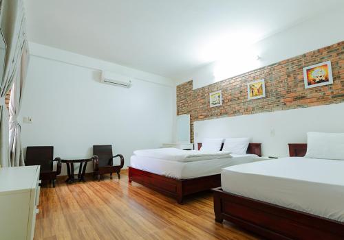 a bedroom with two beds and a brick wall at Loankim Homestay in Hue