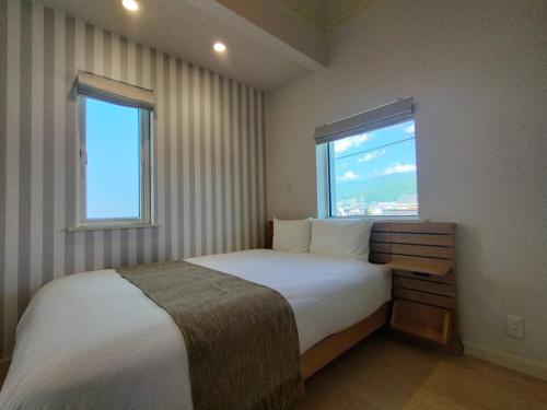 a bedroom with a large bed with a window at マークヴィラスイート in Shimo-suwa