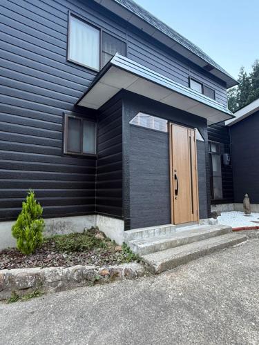 a house with a brown door on the side of it at Kuro House Myoko in Myoko