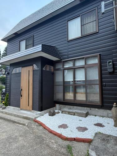 a black house with a brown door and a driveway at Kuro House Myoko in Myoko