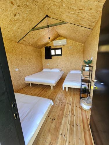 two beds in a room with wooden floors at מאי טאי ויליג' - 8 בקתות מהממות מול הנוף in Mas'ada