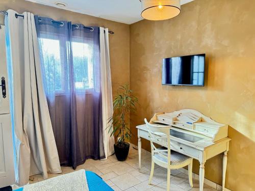 a room with a desk and a tv on a wall at Les Roses de Montherlant in Montherlant
