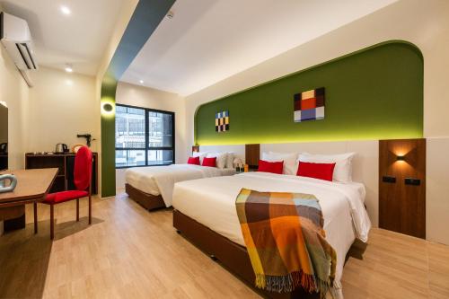 a hotel room with two beds and a desk at Lilybeth Hotel Pratunam in Bangkok